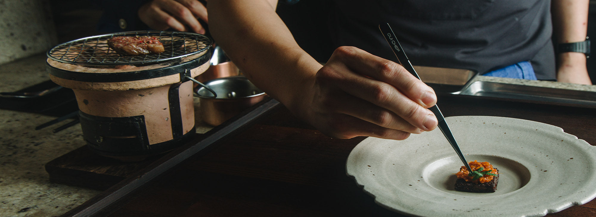 Expert chef using Oui Chef straight tweezers to plate a dish