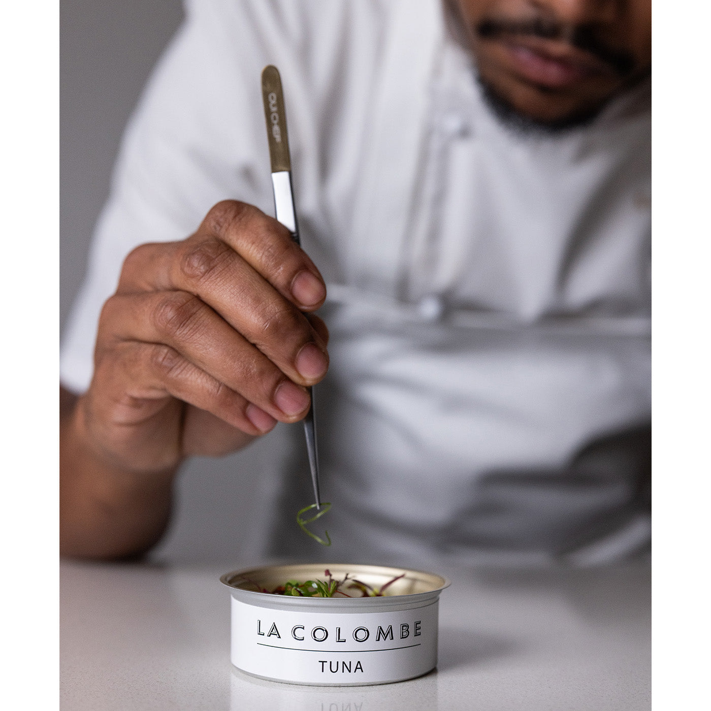 Person using Oui Chef Tweezers  to serve tuna from a can labeled 'La Colombe Tuna'.